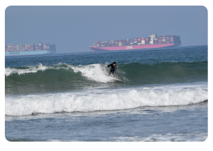 A surfer with container ships lining up south of Long Beach, CA